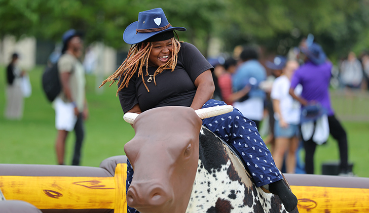Cemelia Chaney, an exploratory studies undergraduate student, laughs as she rides the mechanical bull.
