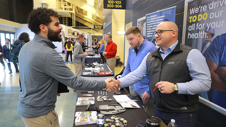 Saif Alhussini, from left, a civil engineering senior, networks with Anthony Goucher and Bill Bucker of the Spicer Group at the Spring 2025 Engineering Career Expo.