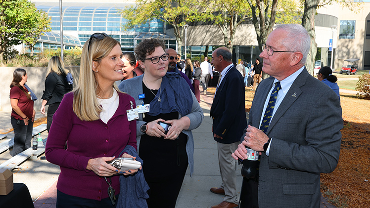 Sara Wisniewski, senior associate general counsel, left, and Kim Steele, clinical risk manager and legal nurse specialist, talk with Holloway during the HSC event.