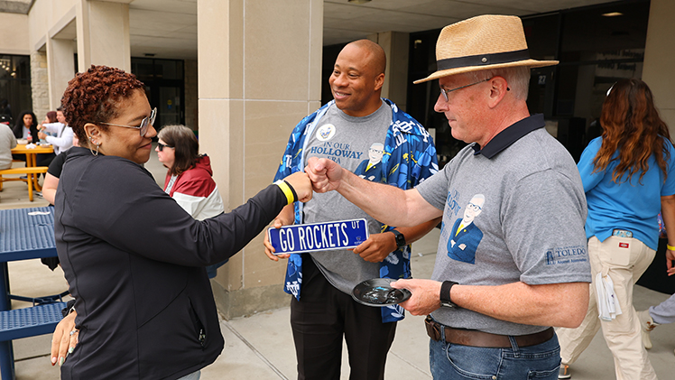 Jamese Greenwade, a political science senior, gives Holloway a fist bump during the barbecue as Dr. Sammy Spann, vice provost and dean of students, watches.
