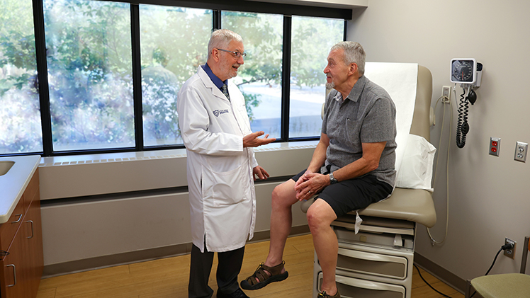 Photo of Dr. Blair Grubb, a cardiologist with UToledo Health, as he speaks with his longtime patient Chris Bowers. Grubb diagnosed Bowers with POTS 20 years and has successfully helped him manage his disease.