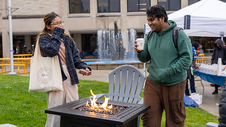 Yash Thakare, a senior in information technology, and Benisha Gurung, a junior in cosmetic science and formulation design — UToledo’s Homecoming Queen and King — share a laugh around one of the festival’s firepits.