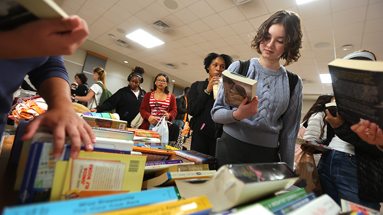 Natalie Mahnke, a freshman in pharmacy, looks at "Whatever Life Throws at You," a novel by Julie Cross, during the Rocket Thrift Shop event.