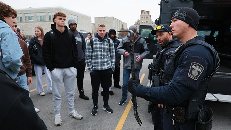Sgt. Gabe Greenwald, left, and Spencer Clark discussed the team, its mission and its demands with members of the student organization before inviting them to check out their armored vehicle and specialized equipment in the parking lot adjacent to the Health and Human Services building. The latter included a ram and a tool to gain entry into outward-swinging doors.