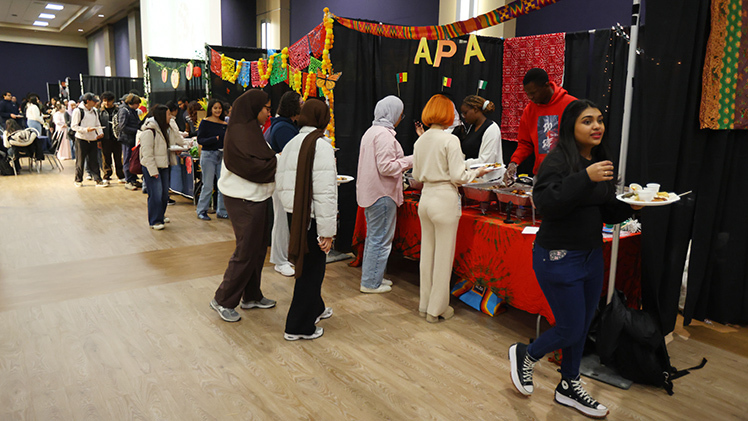 Photo of students lined up to sample food at various booths at the International Students Association’s I-Village on Wednesday at Thompson Student Union Auditorium.