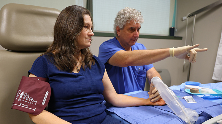 CarrieAnne Campbell, left, listens as Dr. Martin Skie, a UToledo Health orthopaedic surgeon, explains what he's seeing on an ultrasound of her wrist as he prepares to perform a minimally invasive, in-office carpal tunnel release procedure in late November. Campbell, an executive assistant at UToledo, was back to work four days later.