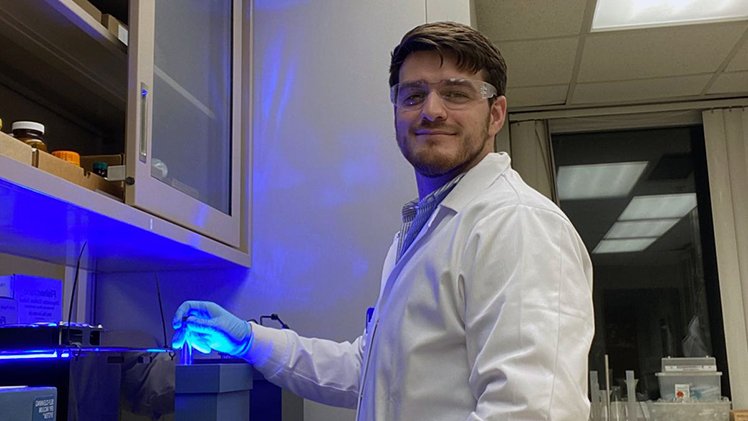 Graduating Dec. 13 with a biochemistry degree, Glenn Chambers’ path is rooted in science and service. He is posing in a lab.