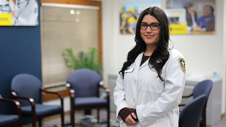 Portrait of Mireya Rivas in her College of Pharmacy white coat. She graduates Saturday with her bachelor of science degree in pharmaceutical sciences.