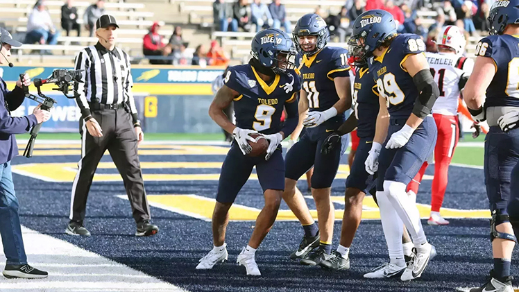 Toledo football players celebrate in the end zone after scoring a touchdown.
