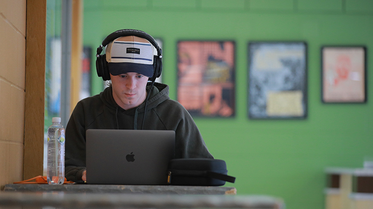 Photo of a virtual student attending class remotely on his laptop.