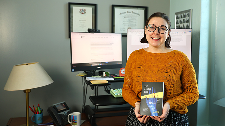 Portrait of Dr. Rebecca Monteleone holding her recently published book, “The Double Bind of Disability,” which examines how disabled people are expected to manage their bodies through technology, yet are often denied authority over those decisions.