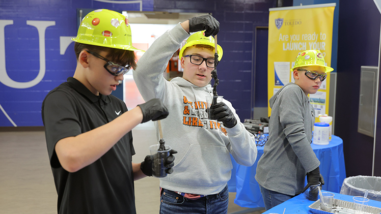 Domanick Taormina examines the magnetic slime he and his classmates Clinton Eitniear (at left) and Grady Proudfoot (at right) are creating during the Introduce a Middle Schooler to Engineering event.