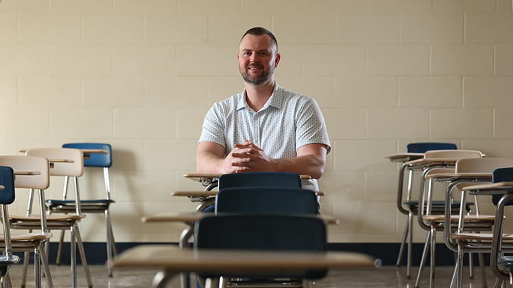 Portrait of Dr. Brandon Wood sitting in a classroom. He is a leader in school-safety research and an associate professor in the College of Health and Human Services.