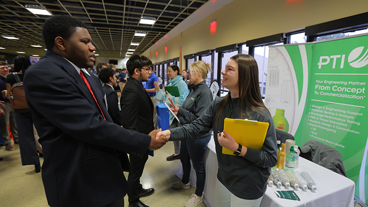 Kaobi Ugwu, a junior in mechanical engineering, and Addy Schmiedebusch, a project engineer for PTI, shake hands at the Spring 2006 Engineering Career Expo.