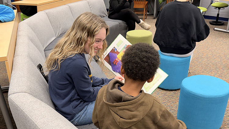 A female University of Toledo student shares a story with a young boy during a literacy-themed community service event on Monday, Feb. 23.