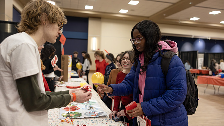 Nandi Grant, right, a junior studying law and social thought, chooses her fortune given by Corbin McDonough, left, a senior studying electrical engineering, as Ariana Levario, a sophomore studying communication and geography and planning, waits in line for her turn.