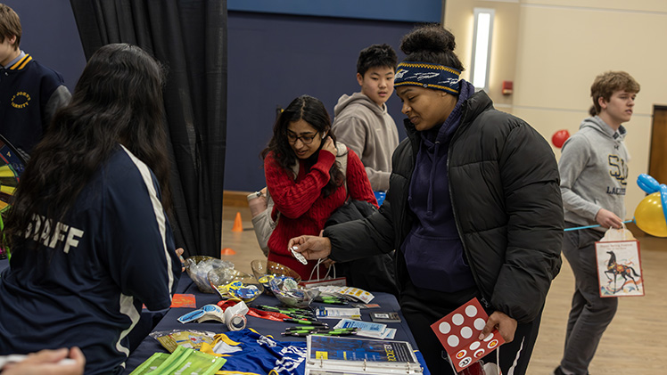Medhawi Chaulagain, a senior in psychology, and Tay Grace, a freshman studying information technology and cyber security, pick out stickers at one of the tables at the Spring Festival Celebration.
