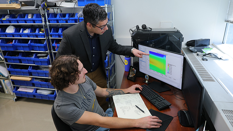 Dr. Raghav Khanna, standing, the Leidich Family Endowed Professor of Power Systems in the College of Engineering, reviews data with Terry Fearn, a master's student in Electrical Engineering.
