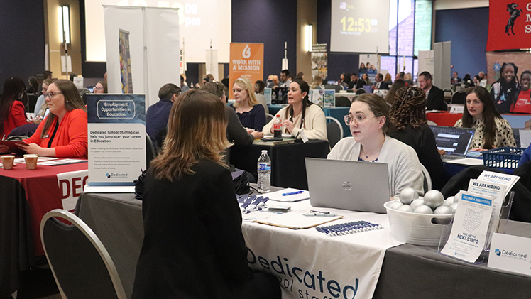 Two women talk at a table during the annual DiscoverEDU Teacher Job Fair on Tuesday at Thompson Student Union Auditorium.