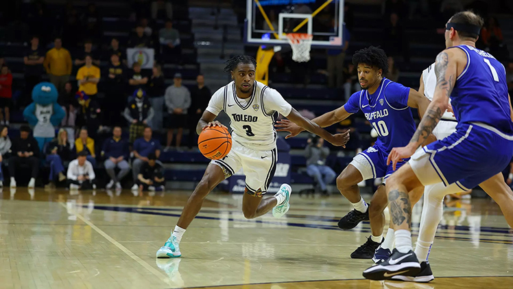 In-game photo of men's basketball player Junior Sonny Wilson dribbling the ball around other players.