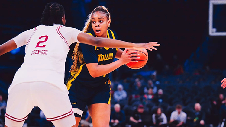 Sophomore Miriam Diala looks to pass the basketball as she is guarded by another player.