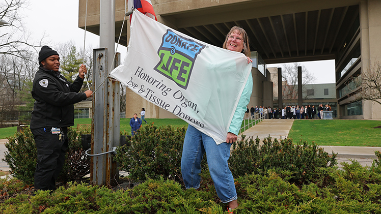 The Donate Life flag is raised by Kandy Takas of Millbury, Ohio, who received a lifesaving kidney at UTMC in 2000.