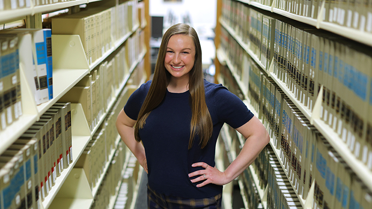 Portrait of graduating law student Megan Rockey, who is standing in the law library.