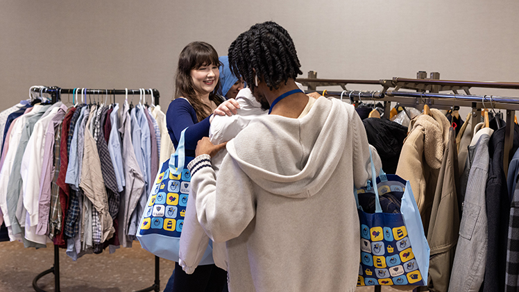 Francesca Holmes, a junior studying medical laboratory science, hands a jacket to her friend, Nathaniel Williams, a junior studying art history and visual arts, to try on while the pair shopped.