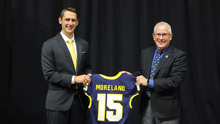 Tom Moreland and UToledo President James Holloway pose for a photo while holding Morelan'd football jersey with the No. 15 and his name on it.
