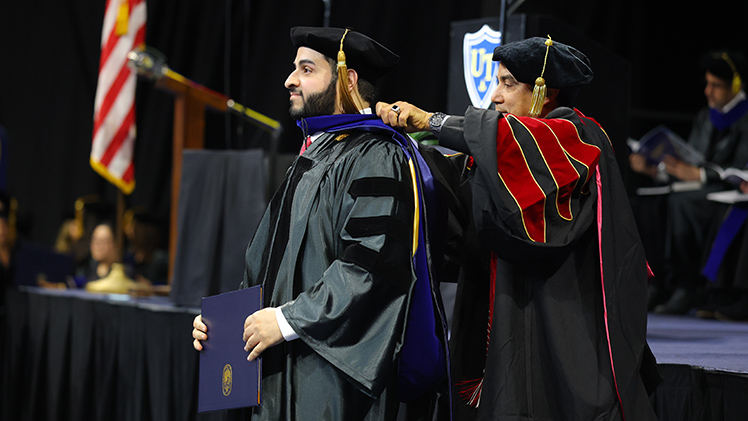 Ahmed Alotaibi receives his doctoral hood from Dr. Youssef Sari, professor and vice chair of pharmacology and experimental therapeutics, during UToledo’s doctoral hooding and graduate commencement Friday, May 1, in John F. Savage Arena. Alotaibi graduated with a Ph.D. in experimental therapeutics.