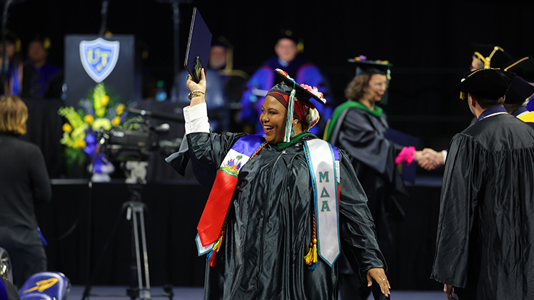 Jessica Smithers smiles brightly as she holds her diploma case high during the ceremony. She earned a Master of Social Work degree.