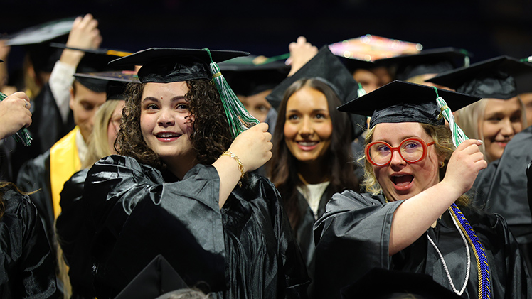 Mariana Meza, left, and Hannah Muren move their tassels from right to left, officially marking their status as alumni, during the afternoon commencement ceremony. Both graduated with Bachelor of Social Work degrees.
