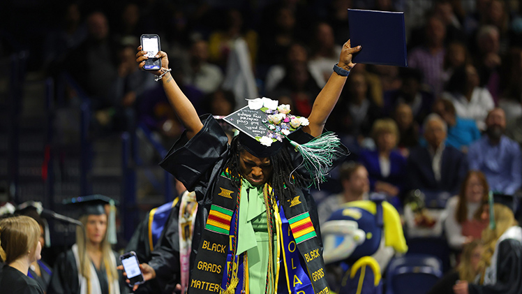 Nyasia Mathis raises her arms in a triumphant celebration of her academic journey after graduating with a Bachelor of Social Work degree during UToledo’s Saturday afternoon ceremony.
