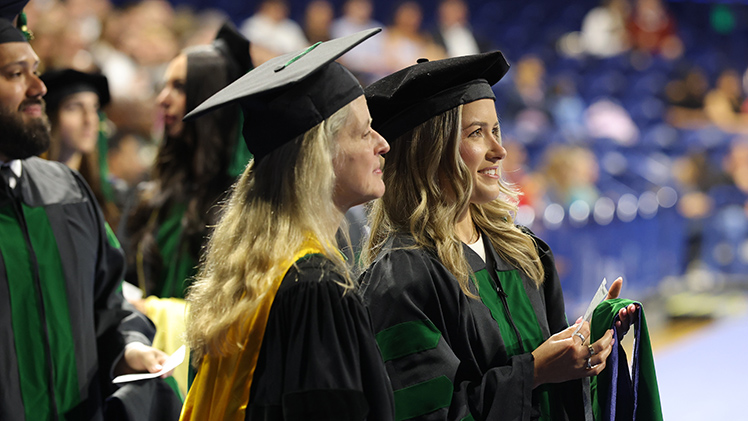 Dr. Bryce DeLong watches the hooding ceremony as she waits with Dr. Laurie Gottwald, chief of dermatology.