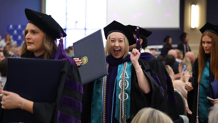 The University of Toledo College of Law celebrated 82 graduates at a commencement ceremony on Sunday in Thompson Student Union Auditorium. THe photo is of a female law graduate smiling as she holds her diploma.