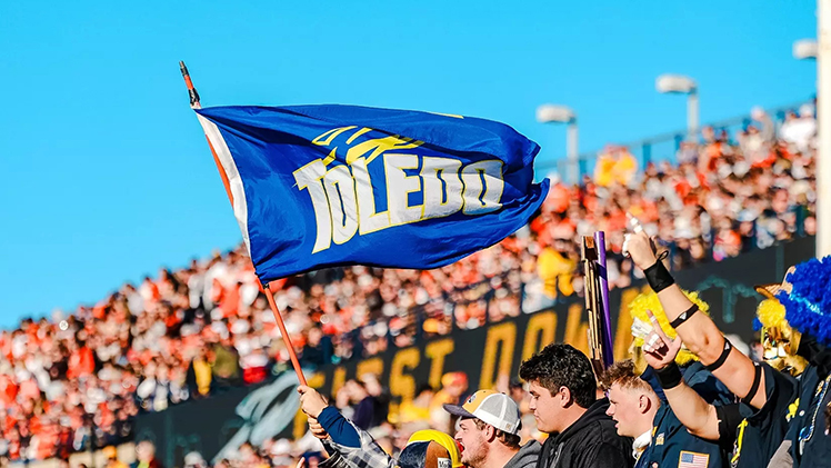 Photo of the Toledo flag in a crowd of Rockets during a football game.