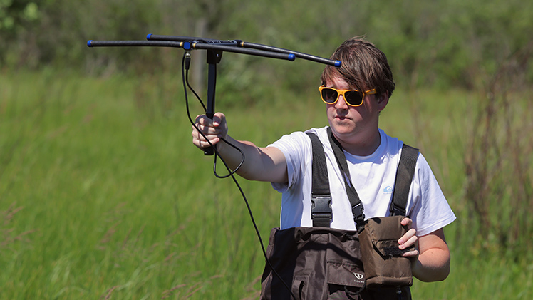 Caleb Lawrence, an environmental sciences senior, uses an antenna and receiver to track a spotted turtle by the unique frequency transmitted by a device attached to her shell. 
