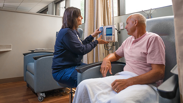Photo of a patient receiving cancer treatment from a nurse.