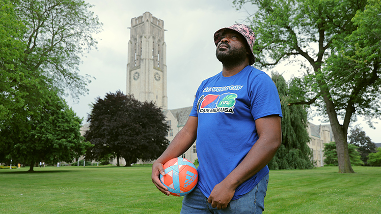 Outdoors portrait of Dr. Shingi Mavima, an assistant professor of history at UToledo. He is holding a soccer ball.