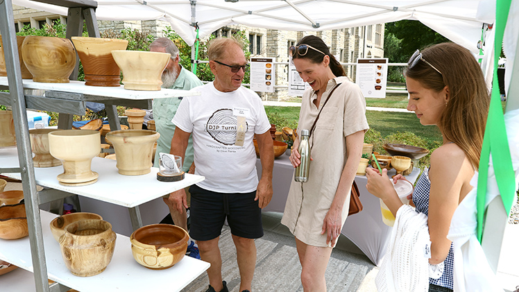 Dave Pienta, left, from DJP Turning, talks with Ellen Rodriguez and Amelia Rodriguez in his tent at Art on the Mall.