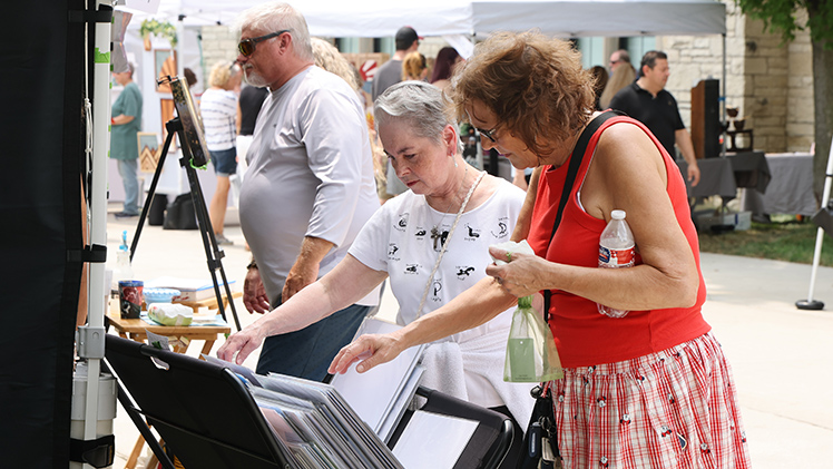 From left, Toledo residents Mary Rust and Sharon Edwards look through prints at the 33rd annual Art on the Mall.