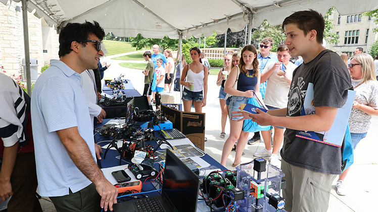From left, Behnam Zaker, president of the UToledo Robotics Club and a Ph.D. student in mechanical engineering, talks with Kenneth Phillips from Toledo at the Campus Crawl.