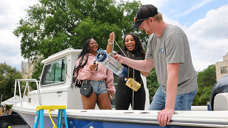 From left, Stephanie McIntosh and Jalicia Atkins, both students at Rogers High School, and Nathaniel Nelson, a UToledo senior majoring in Biology, play a game to capture a water sample from up on the boat as one of several interactive activities at the Campus Crawl.