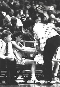 Photo of former Athletics trainer Desiree Hillmon tending to a women's basketball player mid-game.