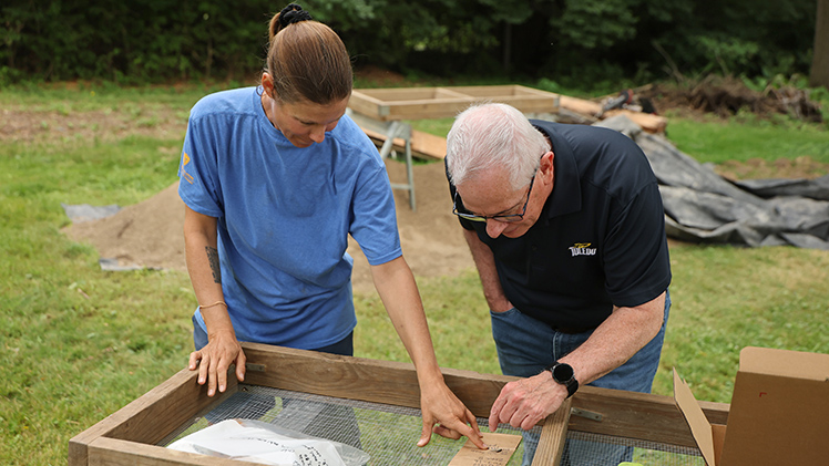 Dr. Melissa Baltus, left, the associate professor of anthropology teaching Field Methods in Archaeology, shows UToledo President James Holloway an artifact uncovered by students at a private-property site adjacent to Fort Miamis in Maumee.