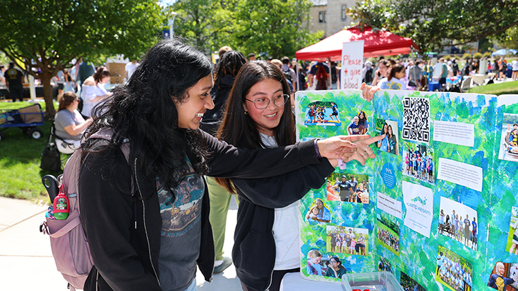 Two female UToledo students look at a poster during a Campus Involvement Fair event.