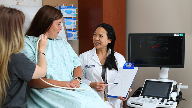 Dr. Duangnapa Cuddy reviews imaging with a patient in the clinic room at the Great Lakes Vascular Institute.