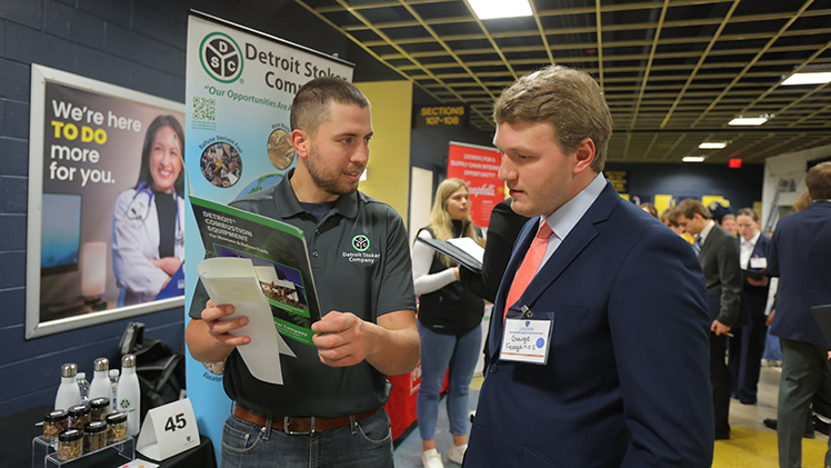 A student networks with a company representative at the Spring Career Expo. The College of Engineering hosts semiannual career expos to support students seeking co-ops, as well as students and alumni seeking post-graduation employment.