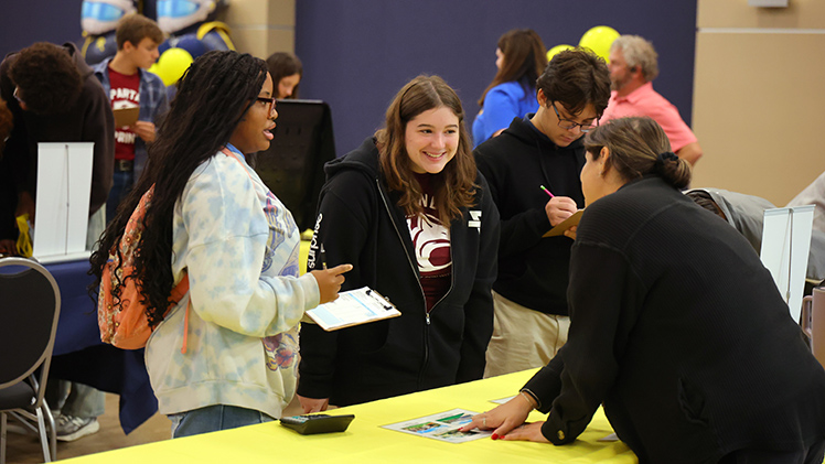 Tabbatha Nieman, right, Office of Student Financial Aid Systems associate director, explains the cost of differently sized houses to Northwest Ohio Classical Academy sophomores, Jasmin Wilson, left, and Maggie Brownfield, center. 