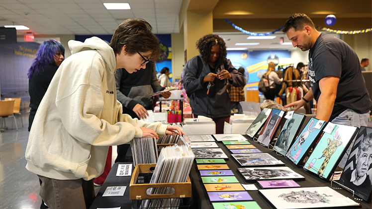 Clayton Houser, a junior in theatre, looks through a selection of wall hangings at the Vintage Market event Tuesday afternoon in Thompson Student Union. Sponsored by the Office of Student Engagement, the Vintage Market featured clothes, posters, photos and more from nearly two dozen vintage and handmade vendors.